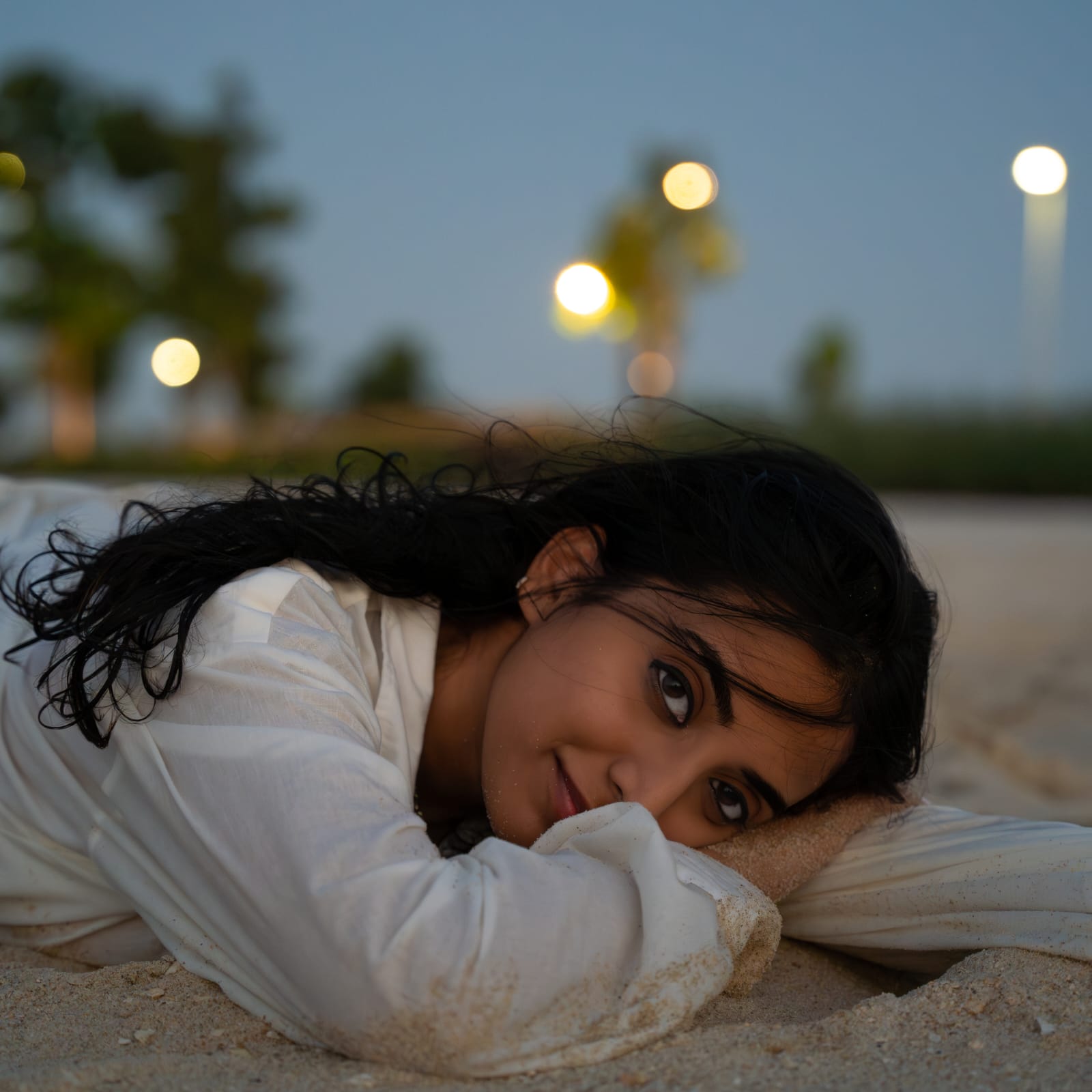 Pooja Venugopal resting on the sand during a beach photoshoot