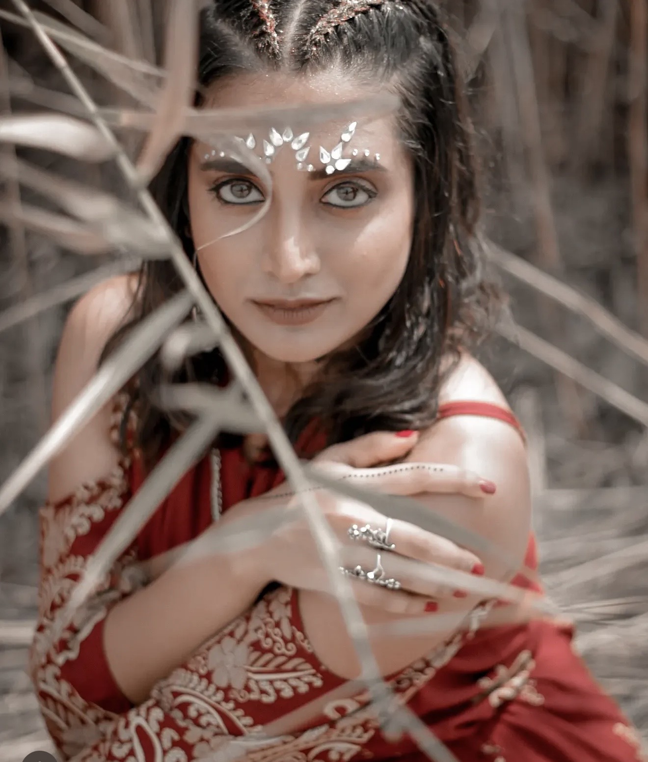 Pooja Venugopal in a red outfit with jewelled makeup